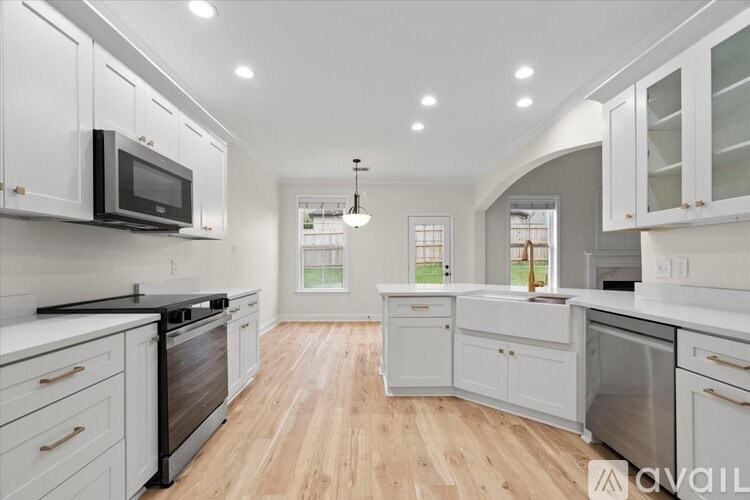 A kitchen with white cabinets and a black microwave.