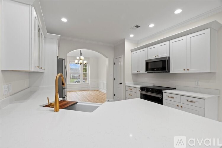 A modern kitchen with white cabinets and a wooden island.