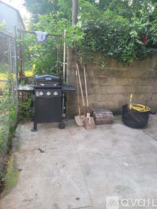 A black grill is on a patio next to a wall.