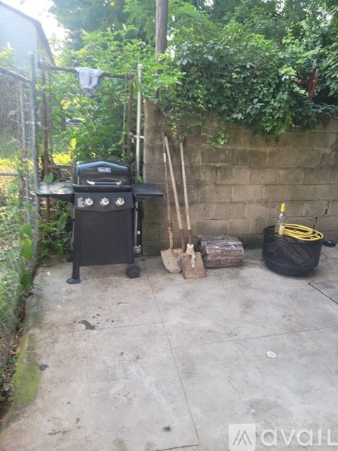 A black grill is on a patio next to a wall.