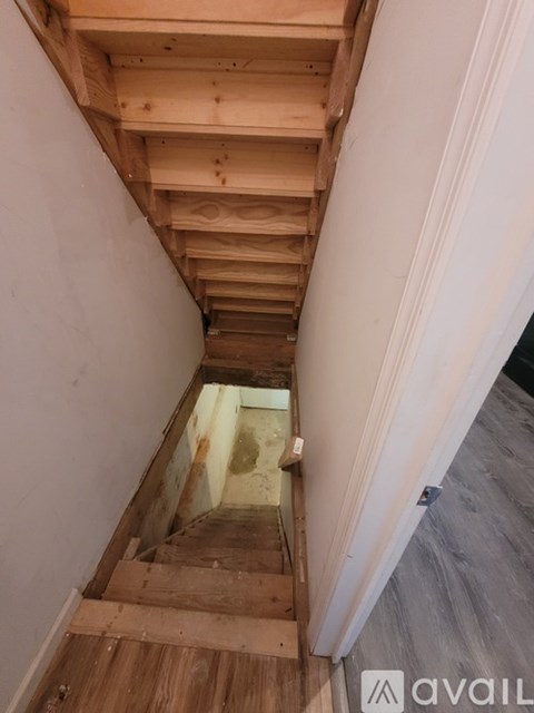 A wooden staircase with a white wall on the left side.