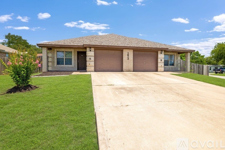 A house with a brown roof and a driveway in front of it.