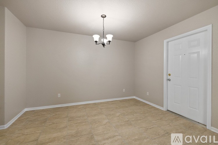 A room with a white door and a chandelier hanging from the ceiling.