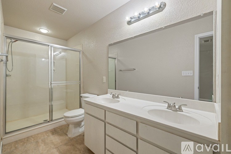 A bathroom with a white sink, toilet, and a glass shower stall.