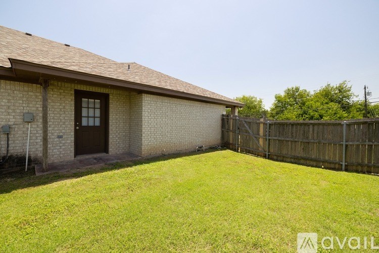 A house with a brown roof and a brown door is surrounded by a wooden fence.