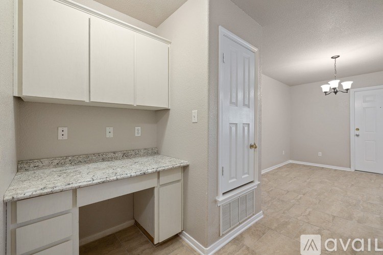 A kitchen area with a marble countertop and white cabinets.