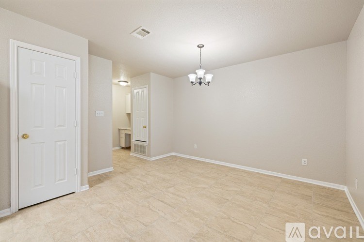 A room with a door, a chandelier, and a window.