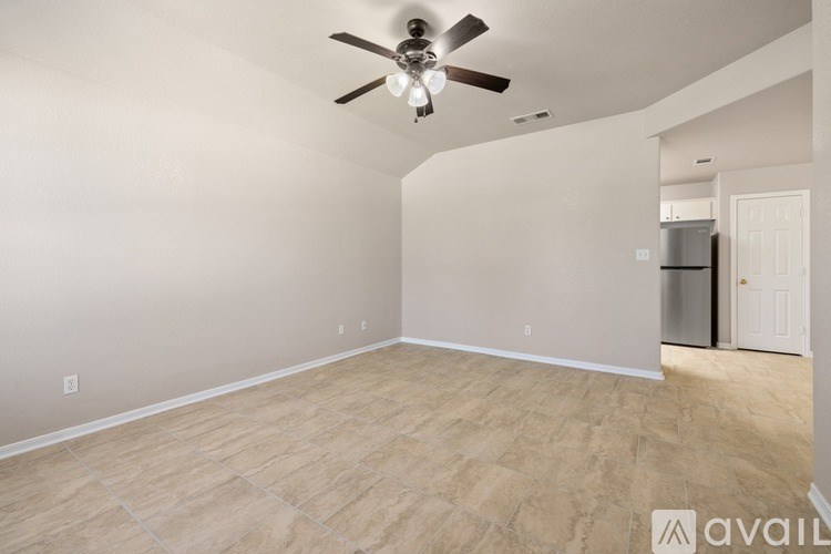 A room with a ceiling fan and a refrigerator in the corner.