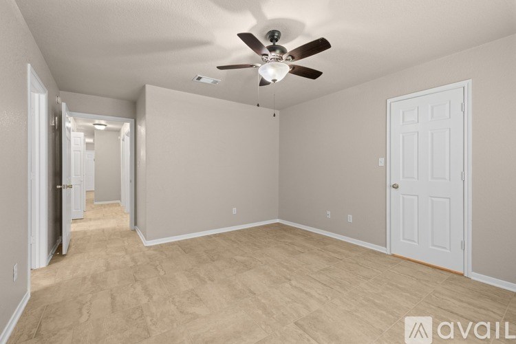 A spacious room with a ceiling fan and light fixture, carpeted flooring, and two doors.