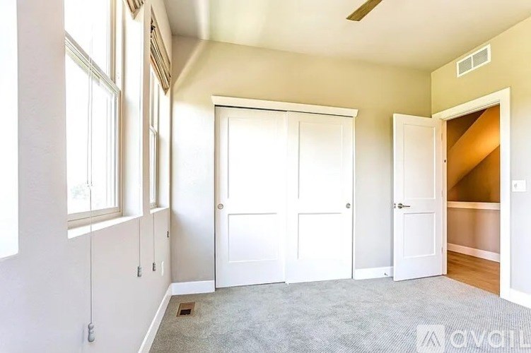 A room with white doors and a window on the left side.