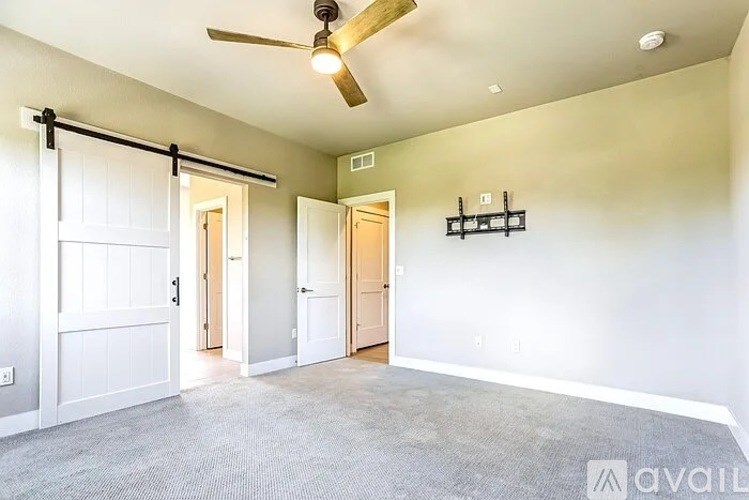 A room with a ceiling fan and sliding doors.