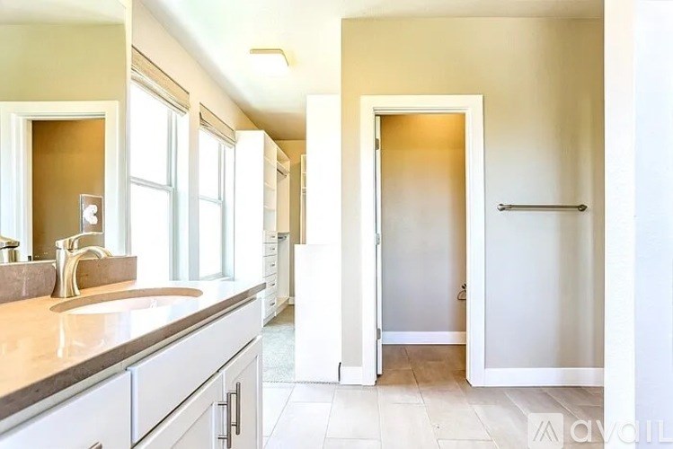 A bathroom with a sink, mirror, and a towel bar.