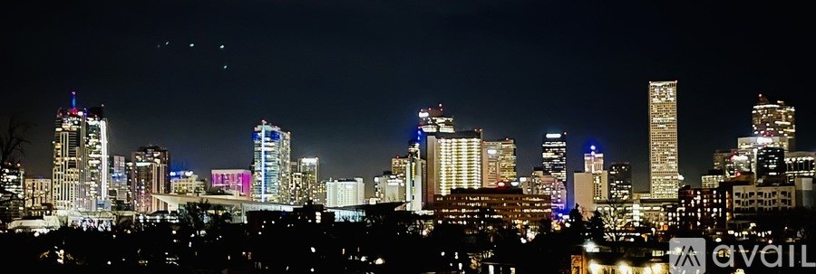 A city skyline at night with various buildings illuminated.