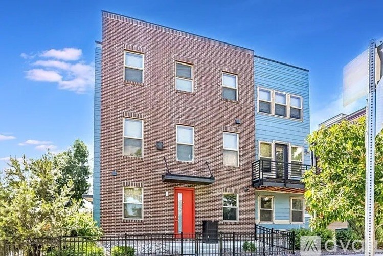 A red door is on the front of a brick building.