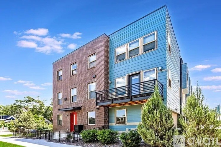 A modern two-story building with a blue exterior and a red door.
