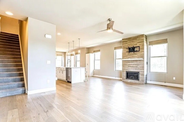 A spacious living room with a staircase and a fireplace.