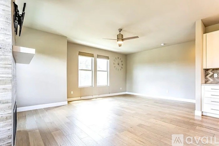 A spacious room with wooden flooring and a ceiling fan.