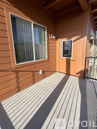 A balcony with a brown wooden wall and a striped grey floor.