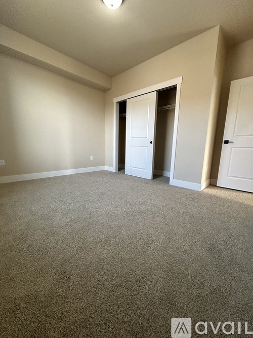 A room with carpeted floor and two white doors.