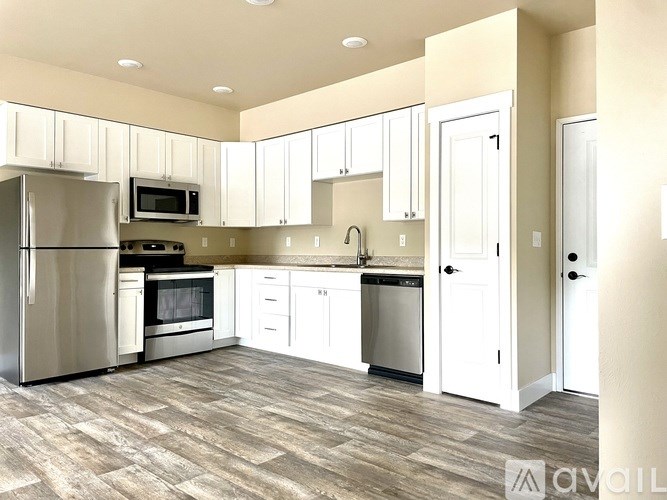 A kitchen with white cabinets and a wooden floor.