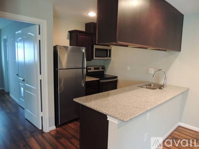 A kitchen with a refrigerator, microwave, and sink.