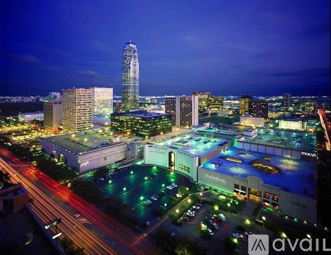 A cityscape at night with a tall building in the background and a parking lot in the foreground.
