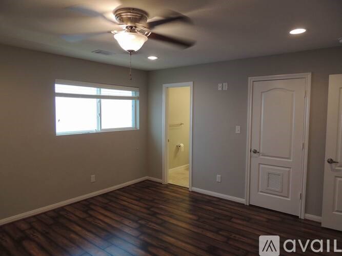 A room with a ceiling fan and wooden floors.