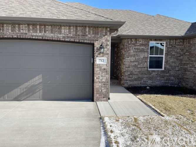 A house with a grey garage door and a brick wall.