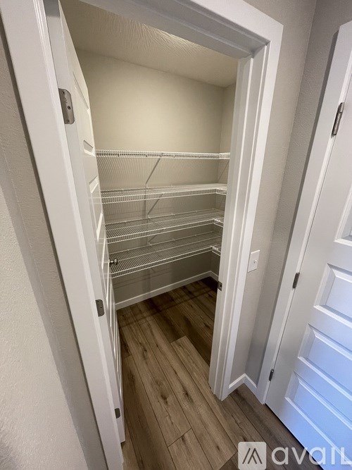 A white closet with shelves and a wooden floor.