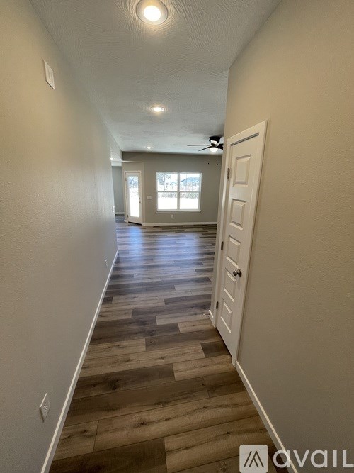 A long hallway with wood floors and white walls.