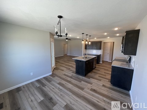 A spacious living room with a kitchen in the background.