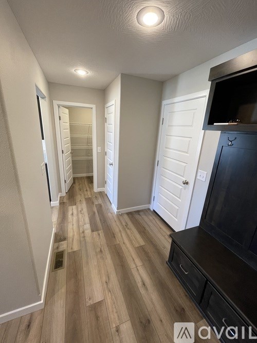A hallway with wood flooring and white walls.