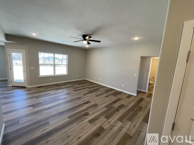 A room with a ceiling fan and wooden flooring.
