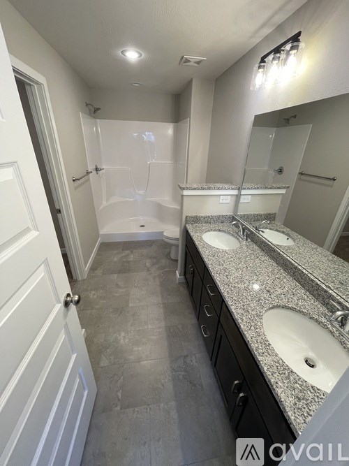 A bathroom with a granite countertop and a walk-in shower.