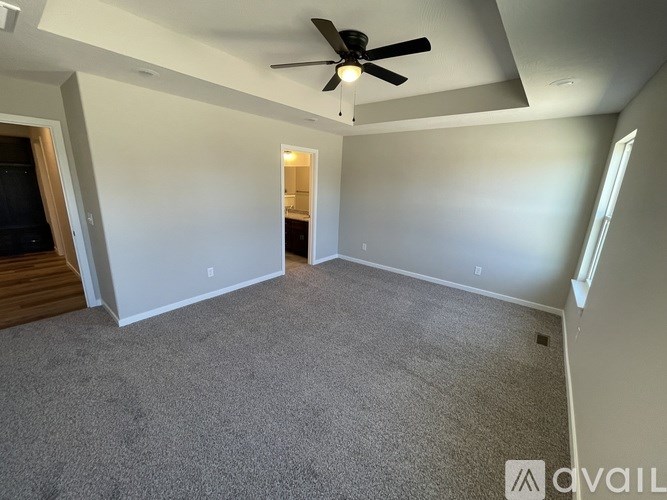 A room with a ceiling fan and carpeted floor.