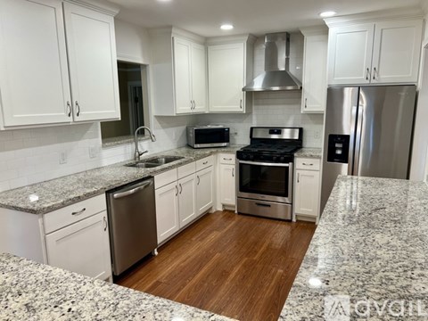 A kitchen with white cabinets and a granite countertop.
