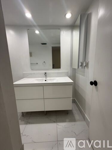 A white bathroom with a sink and mirror.
