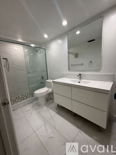 A white bathroom with a toilet, sink, and mirror.