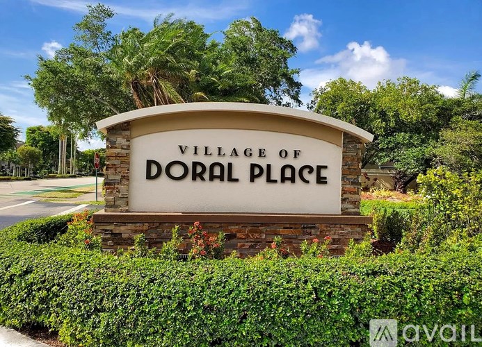 A sign that says "Village of Doral Place" in front of some trees.