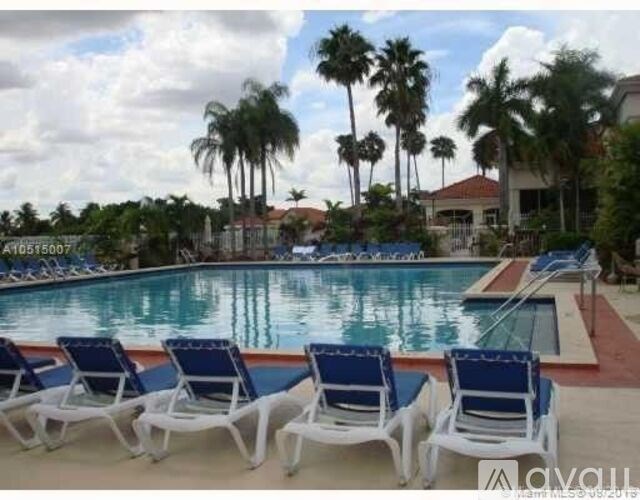 A pool with blue chairs and palm trees in the background.