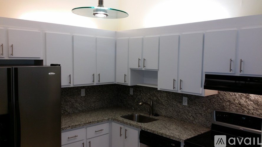 A kitchen with white cabinets and a black refrigerator.