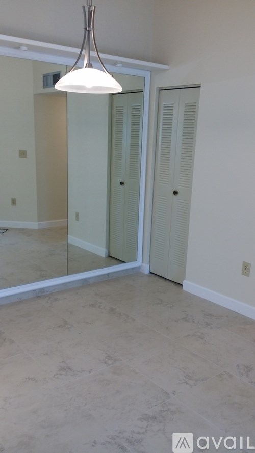 A room with a large mirror and a hanging light fixture.
