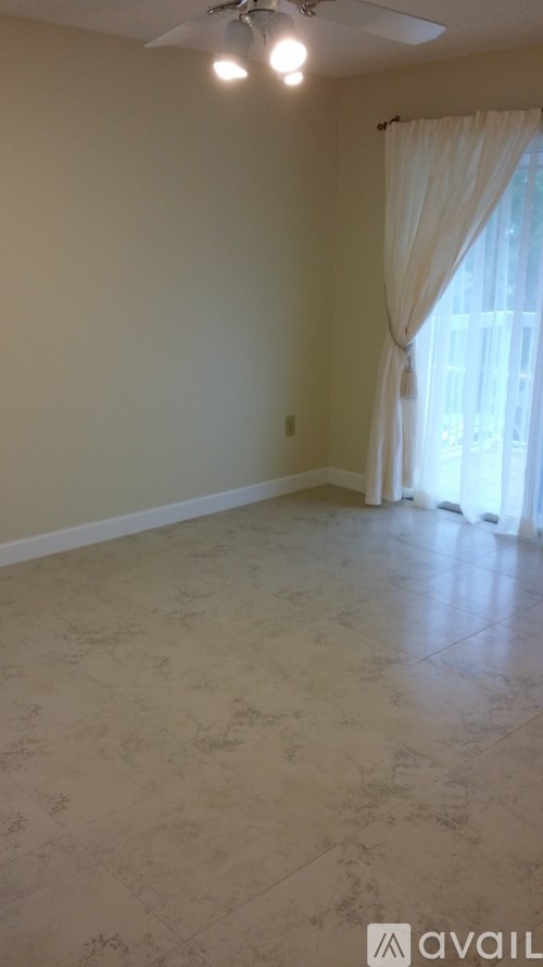 A room with a ceiling fan and a window with curtains.