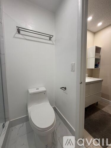 A white toilet in a small bathroom with a towel rack above it.