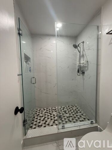 A glass shower stall with a black and white tiled floor.