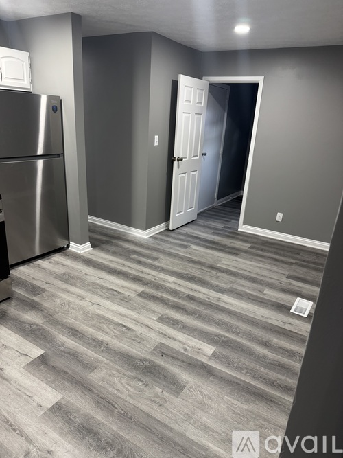 A kitchen with a refrigerator and a doorway leading to another room.