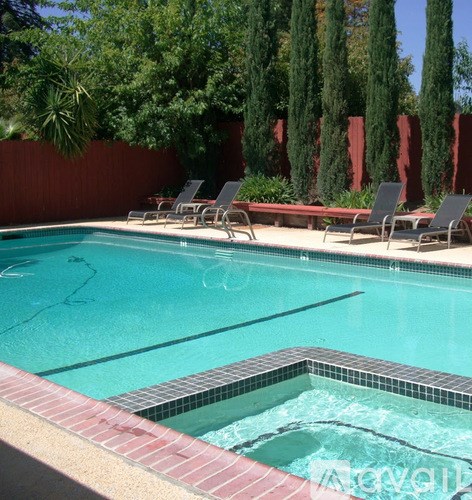 A pool with a red tile border and a small hot tub in the middle.