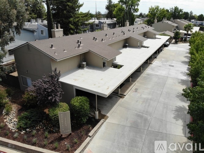 A large building with a grey roof and a parking lot in front.
