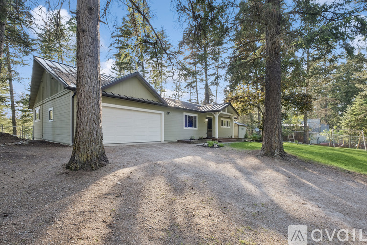 A house with a garage is surrounded by trees.
