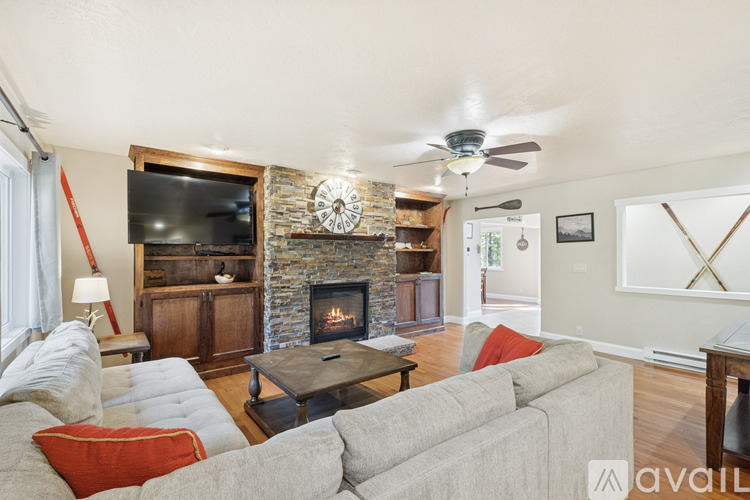 A living room with a grey couch and a stone fireplace.